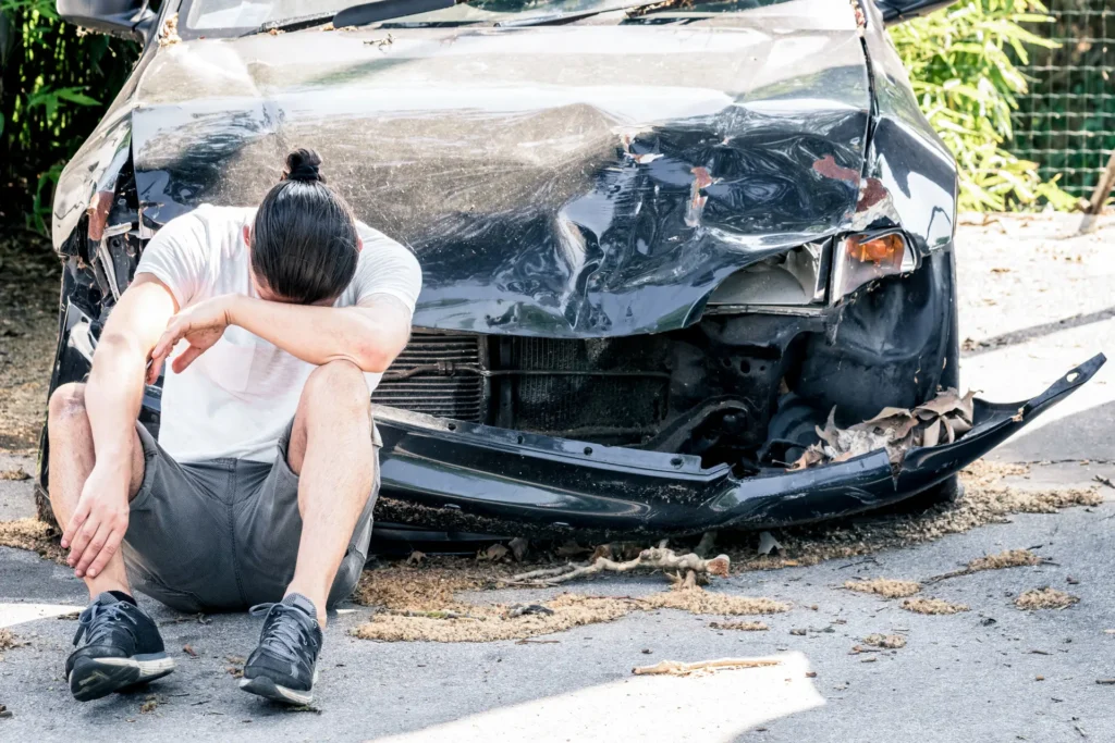 man sat in front of crashed car