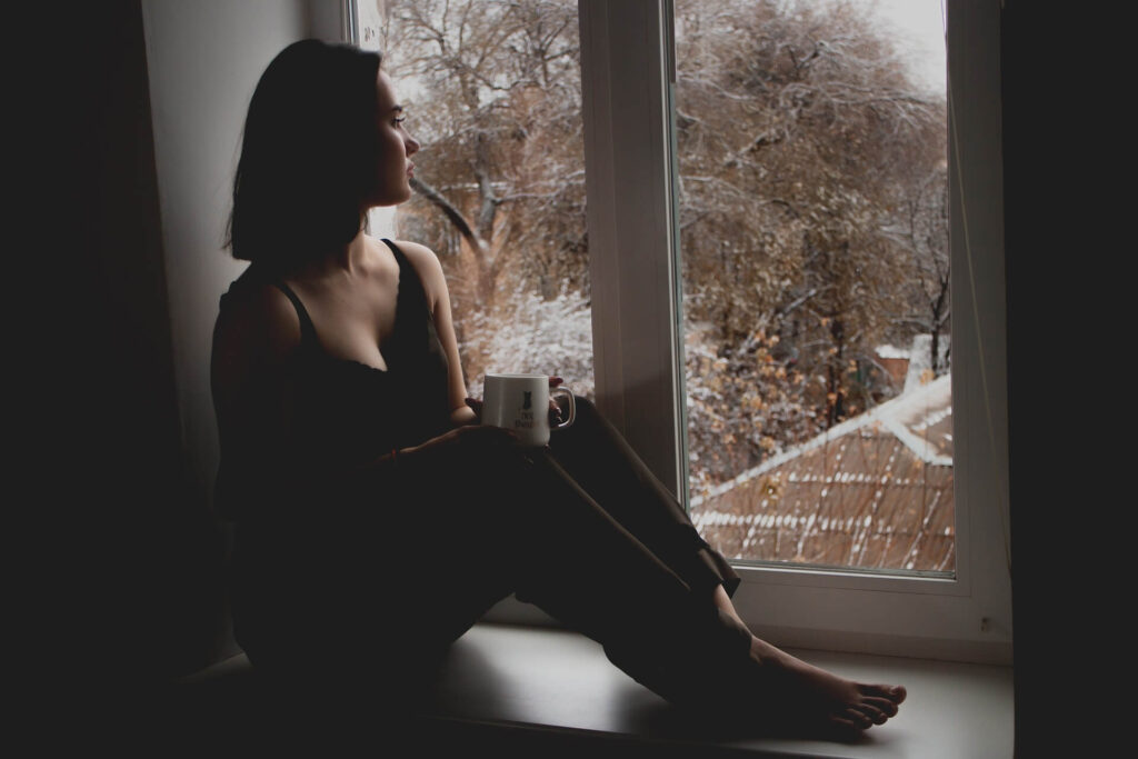 woman looking out of a window looking sad