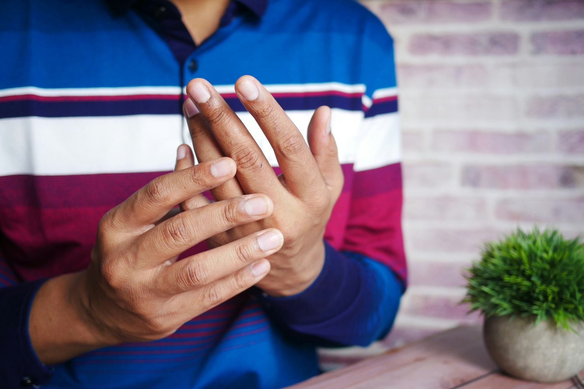 Man in shirt holding hand in pain
