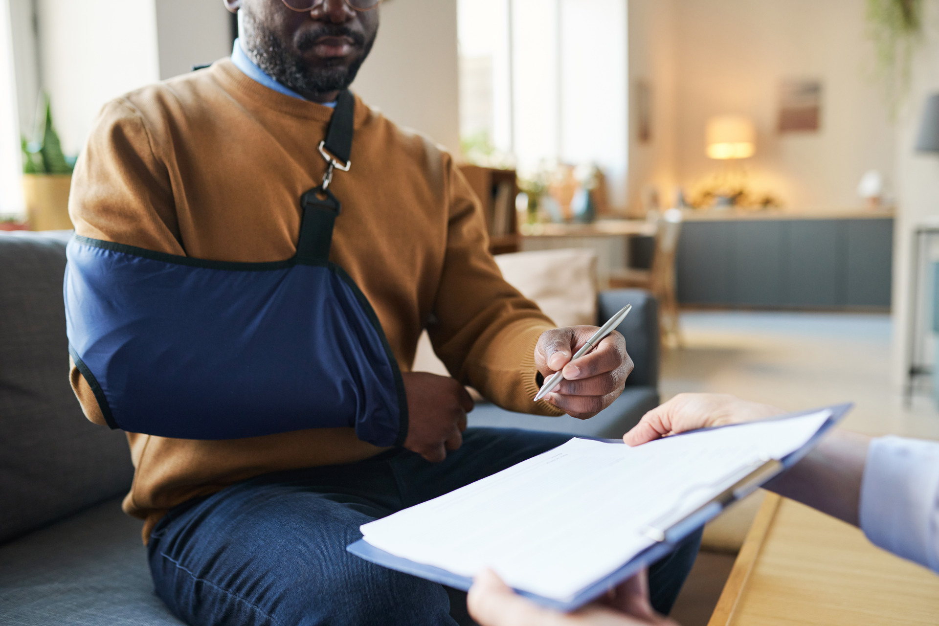 man with arm-sling signing medical documents