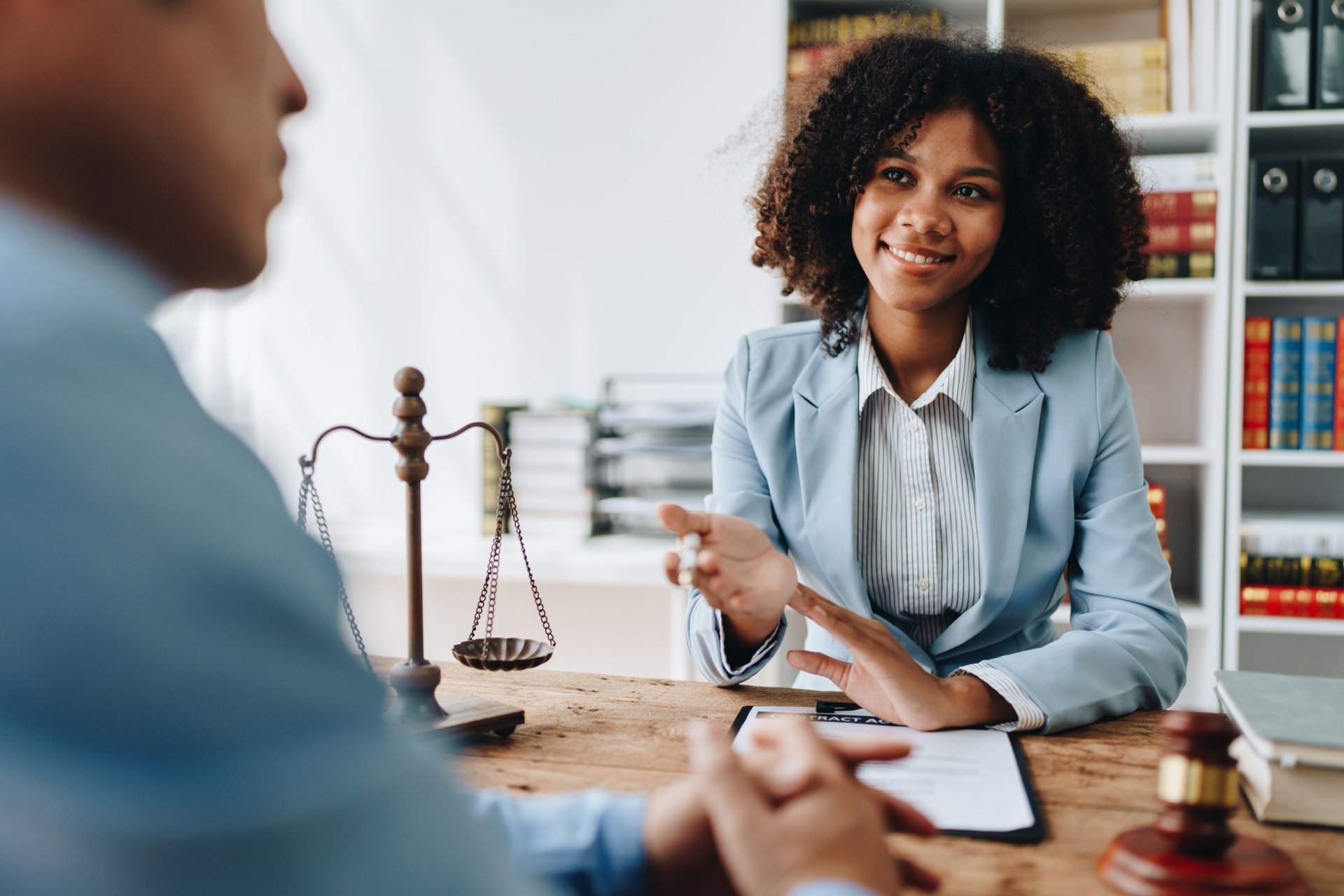 African American female attorney in a blue blazer discussing legal matters with a client in an office setting