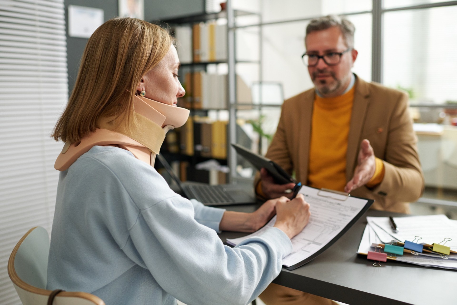 Woman in neck brace filling out insurance paperwork