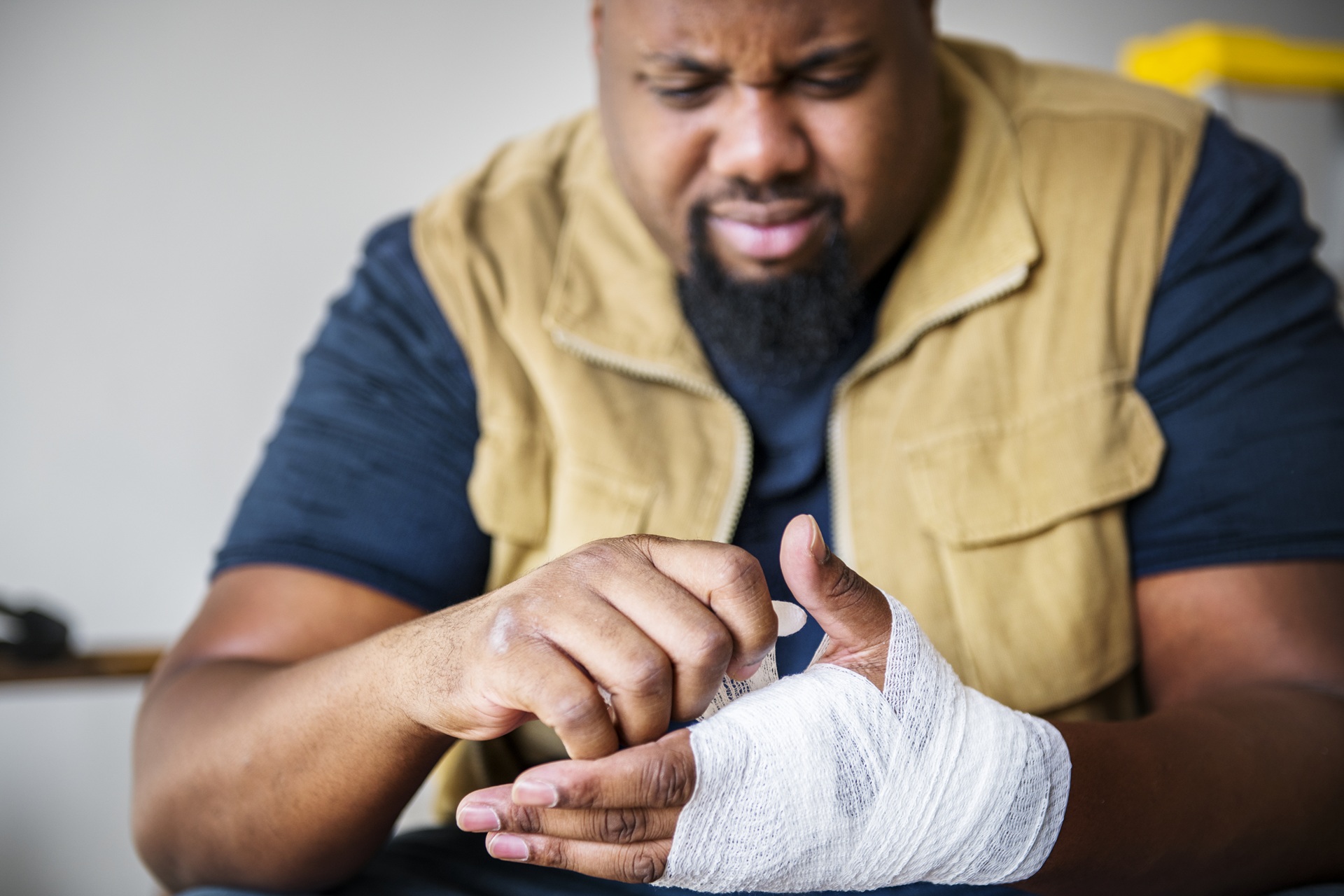 A man is wrapping a bandage around his injured hand