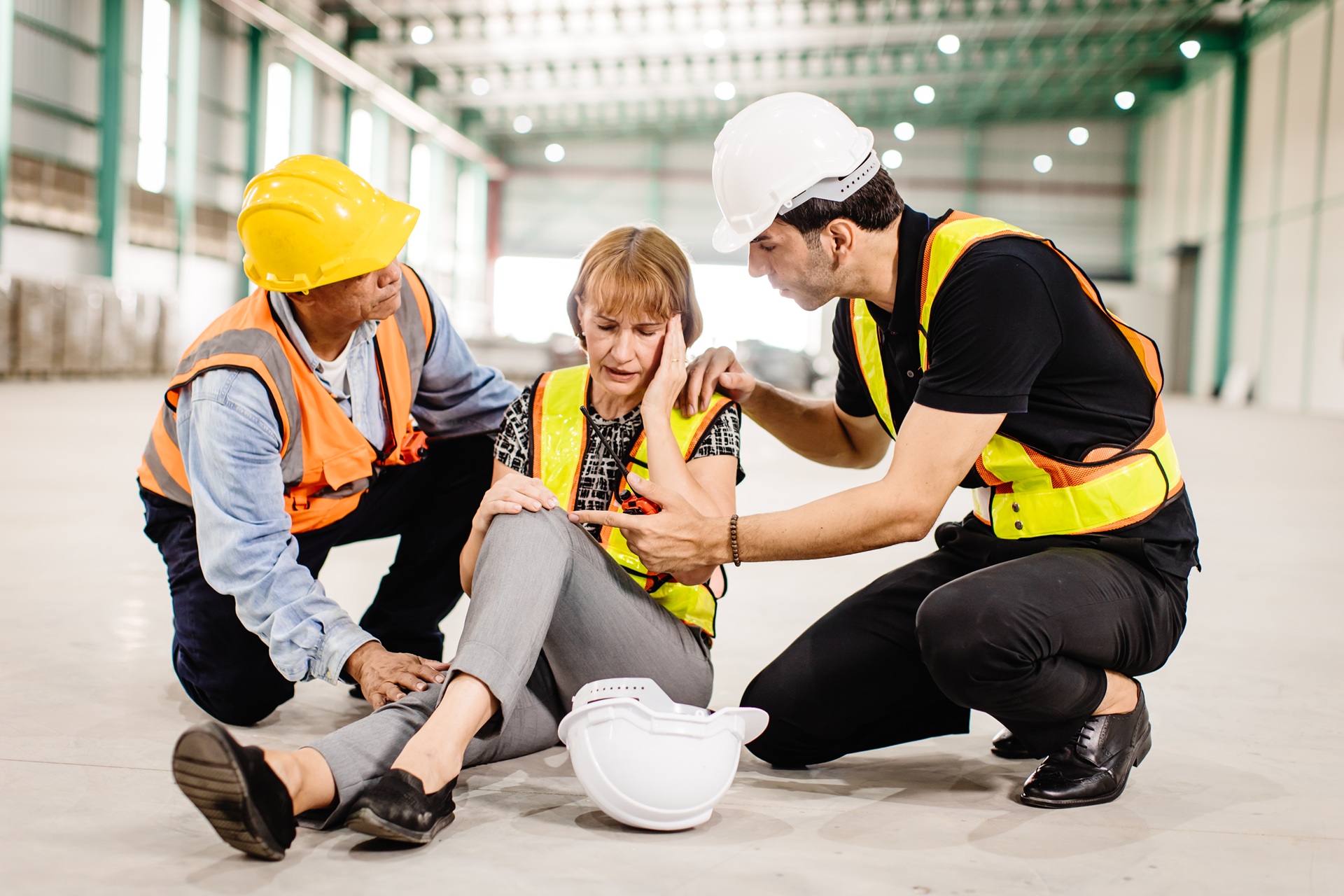 Two workers are helping a female engineer who has fainted at a construction site