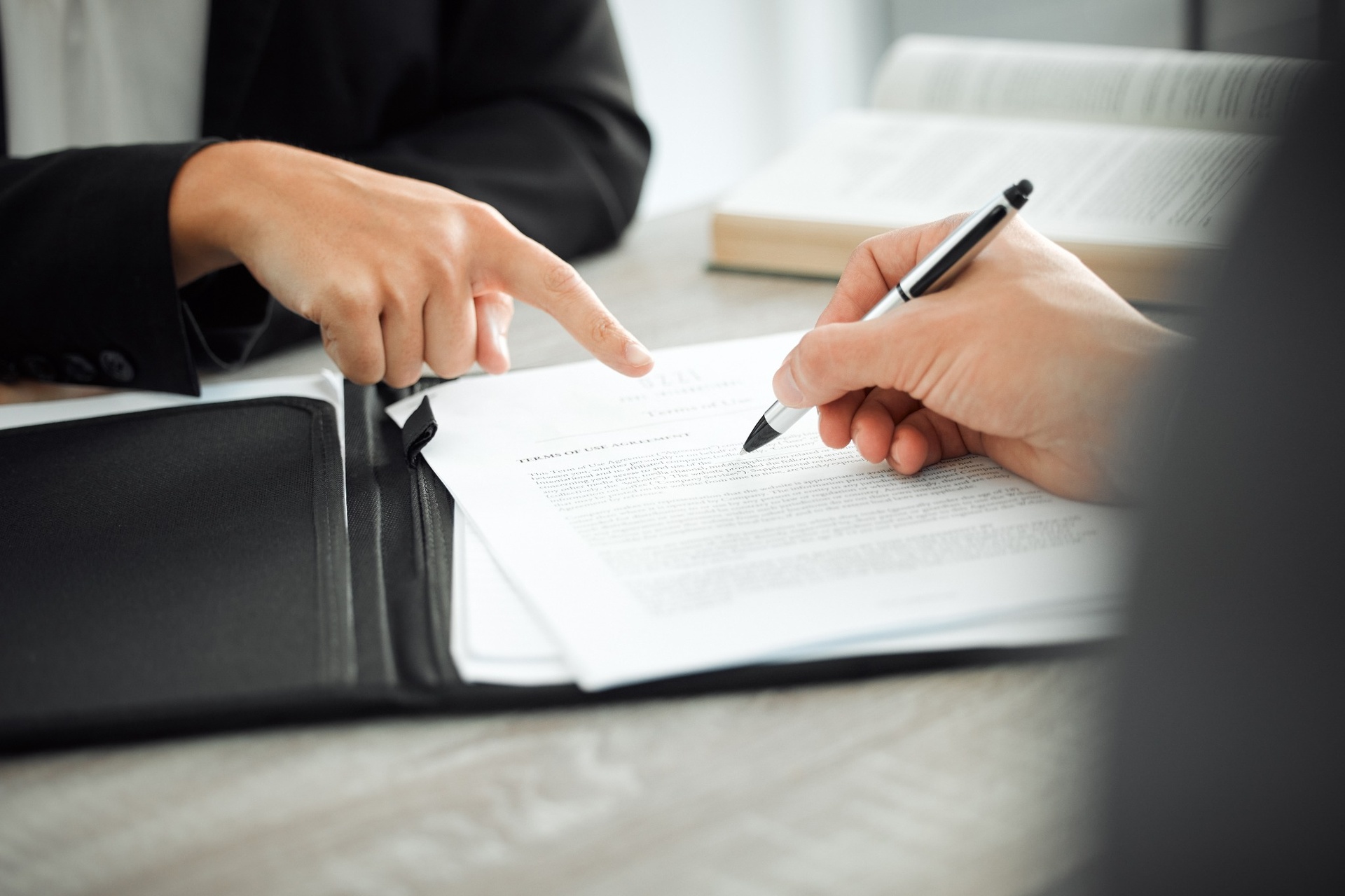 Close-up of two people reviewing and signing a legal contract