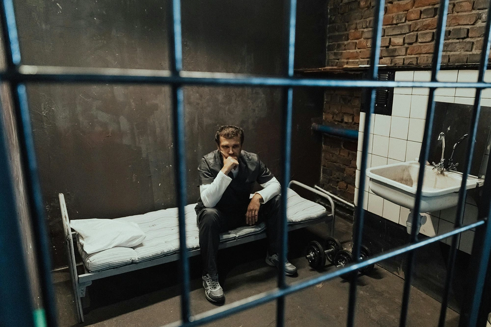 man sitting in the prison bed